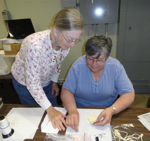 Bev teaching Susie to bead the amulet bag.